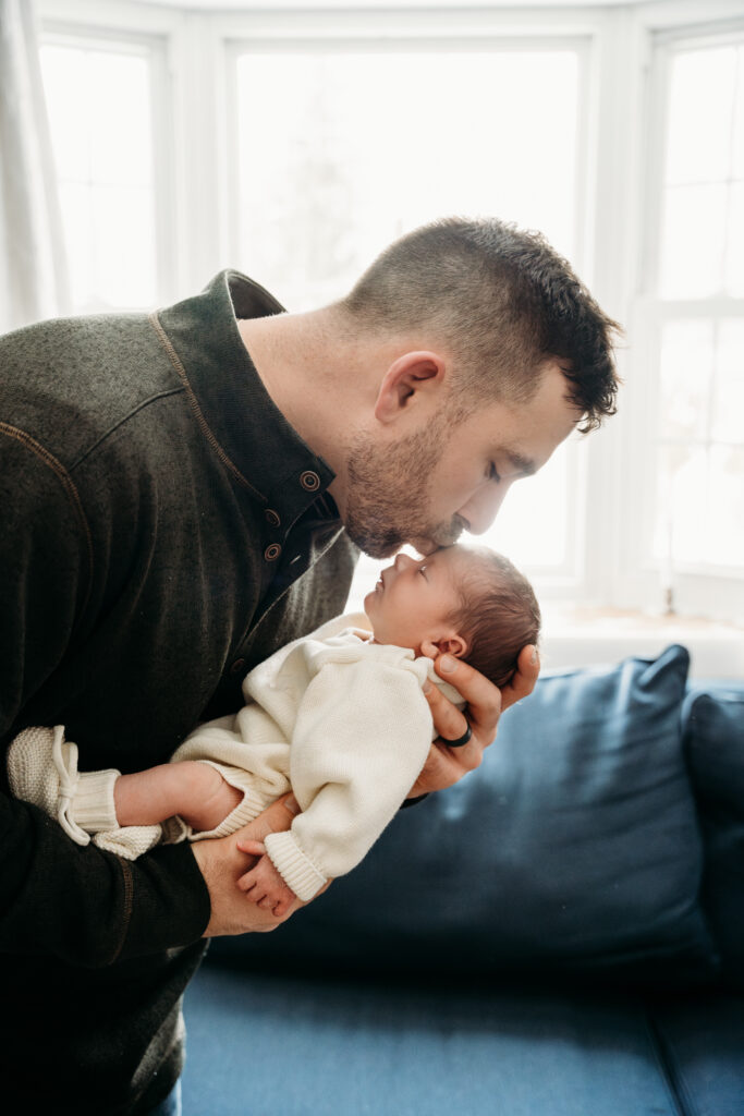dad kissing newborn baby on head