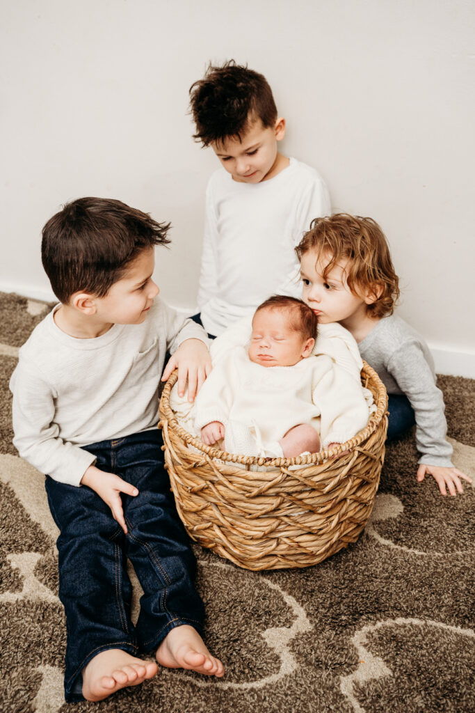 newborn in basket with siblings aroound the basket